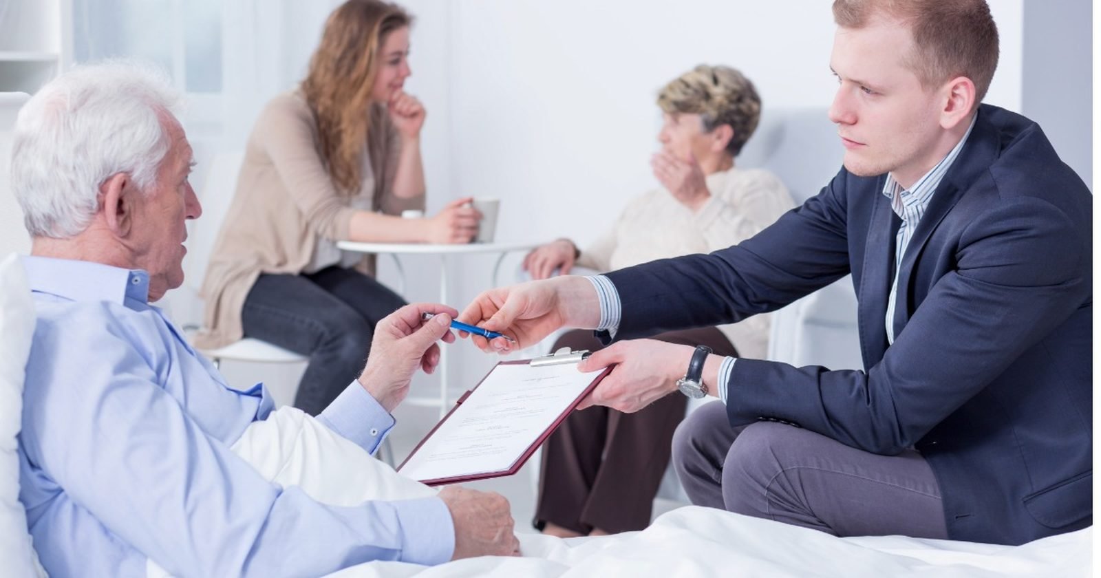 Mobile notary bringing documents to an elderly man for signing at his bedside in a New Jersey care facility, family nearby